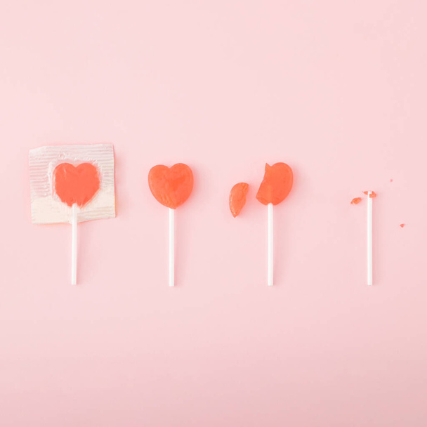4 heart-shaped lollipops on a pastel pink background.Minimal flat lay concept. - Photo, Image