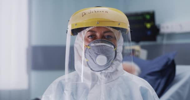 Médico en traje de materiales peligrosos mirando a la cámara - Imágenes, Vídeo