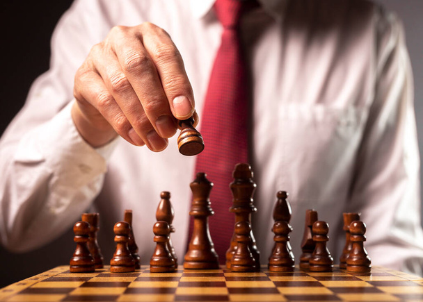 Business financial strategy concept. Businessman making decision and moving chess piece over other chess figures. - Fotoğraf, Görsel