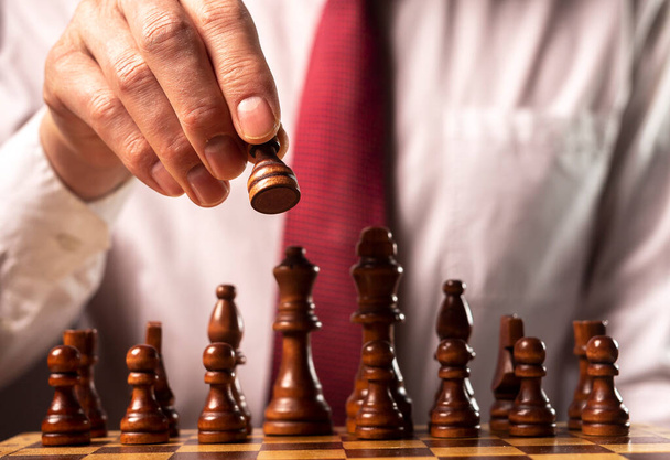 Business financial strategy concept. Businessman making decision and moving chess piece over other chess figures. - Photo, Image