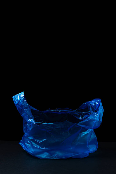 Bolso azul plástico sobre fondo negro. Paquete azul transparente sobre fondo oscuro. - Foto, imagen