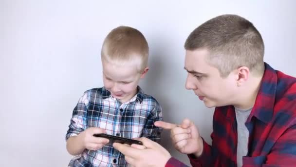 Dad tries to take the child's phone, on which he plays for a long time. The guy does not give up his smartphone and behaves aggressively. Child addiction to mobile phones and video games. - Footage, Video