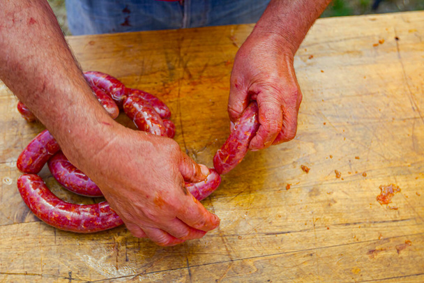Macellaio torce intestino fresco pieno di carne macinata, dividere per fare salsicce circa la stessa lunghezza. - Foto, immagini
