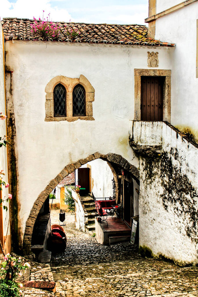 Enge und farbenfrohe Straßen, majestätische Fassaden, Fenster und Balkone des alten Dorfes Obidos, Portugal - Foto, Bild