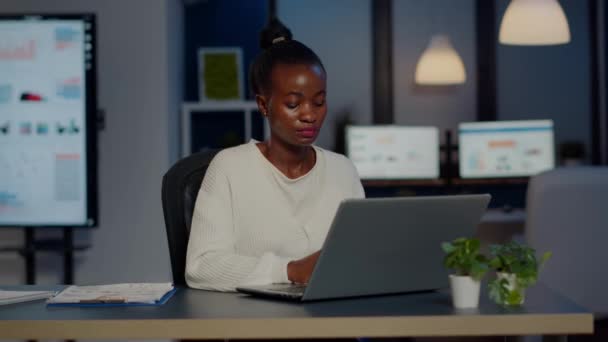 zestresowana afrykańska menadżer kobieta pracuje z wykresami finansowymi nadgodziny - Materiał filmowy, wideo