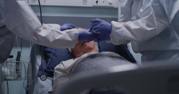 Lekarze pomagający staremu pacjentowi z problemami z oddychaniem - Materiał filmowy, wideo