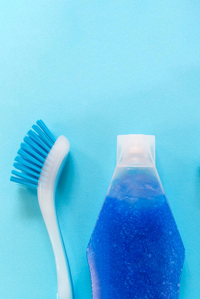 Blue vertical monochrome flay lay with copy space on top of brush and bottle with bubble liquid for cleaning.  - 写真・画像