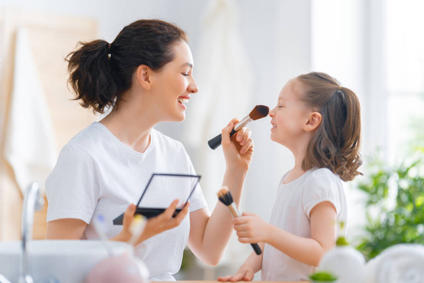 Happy loving family. Mother and daughter are doing make up and having fun. - Photo, image