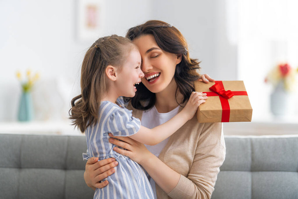 Happy mother's day! Child congratulating mom. Mum and daughter smiling and holding gift. Family holiday and togetherness. - Фото, изображение