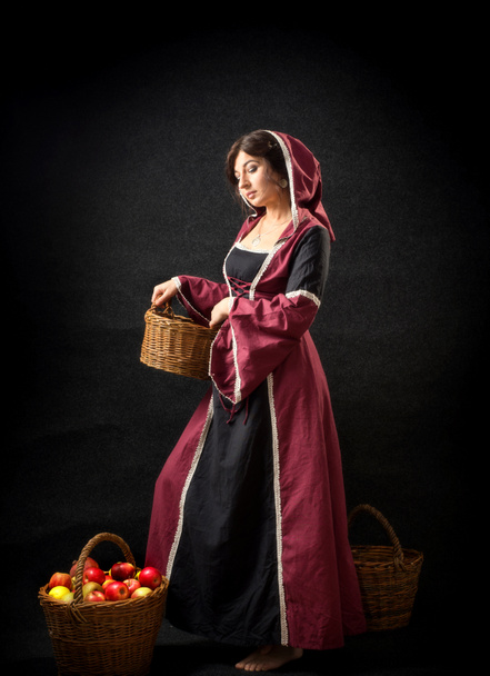 Kapüşonlu ve elma sepetli ortaçağ elbisesi giyen bir kız. Tarihi kostüm. - Fotoğraf, Görsel
