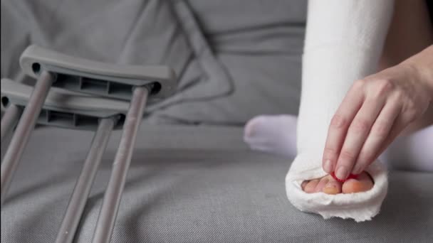Een vrouw in een verbandbeen masseert haar vingers met een massagebal - Video