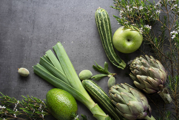 テーブルの上に新鮮な野菜や果物。緑のリンゴ,アーティチョーク,ズッキーニ,アーモンド.アボカドとハーブをコピースペース付きの灰色のコンクリートの背景に。バランスのとれたキッチンコンセプト.  - 写真・画像