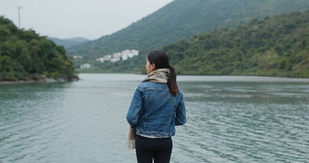 Жінка насолоджується видом на море і стоїть біля причалу
 - Фото, зображення
