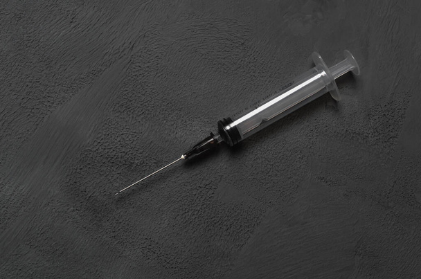 Použitá jednorázová lékařská stříkačka na šedém betonovém pozadí. Detailní záběr. - Fotografie, Obrázek
