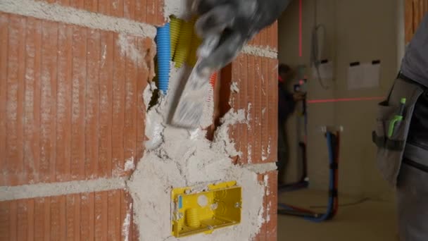 CLOSE UP: Bouwer maakt gebruik van een spatel en beton te bedekken elektriciteitsleidingen. - Video