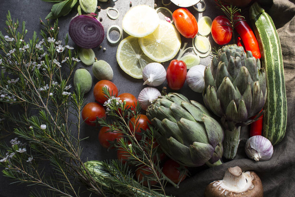 Raw vegetables on a table. Top view photo of fresh artichokes, leeks, cherry tomatoes, onion, pepper, green almond, zucchini, mushrooms and herbs. Food preparation photo.Healthy eating concept. - Photo, Image