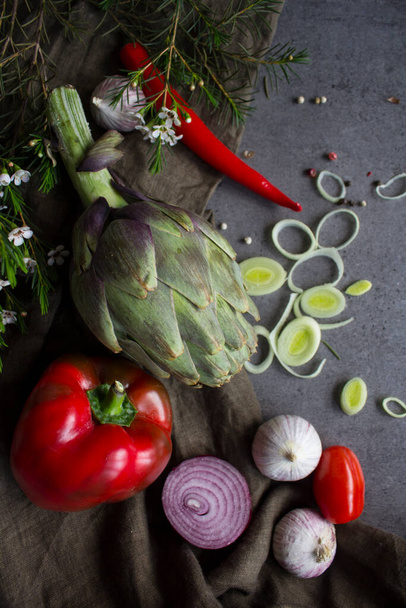 Ωμά λαχανικά σε ένα τραπέζι. Φωτογραφία με αγκινάρες, πράσα, ντοματίνια, κρεμμύδι, πιπέρι, πράσινο αμύγδαλο, κολοκυθάκια, μανιτάρια και βότανα. Φωτογραφία παρασκευής τροφίμων.Υγιεινή διατροφή έννοια. - Φωτογραφία, εικόνα