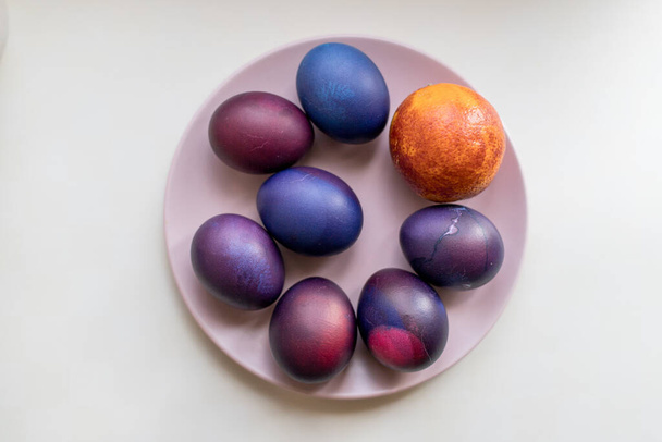 Œufs de Pâques peints en bleu et violet sur fond texturé. Œufs de Pâques dans une assiette. - Photo, image