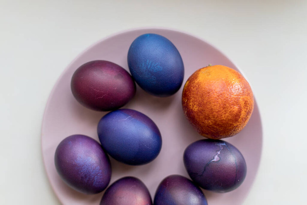 Renkli arka planda mavi ve mor paskalya yumurtaları. Tabakta paskalya yumurtası. - Fotoğraf, Görsel