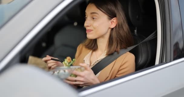 Liiketalouden nainen syö salaattia kuljettajien istuimella autonsa - Materiaali, video