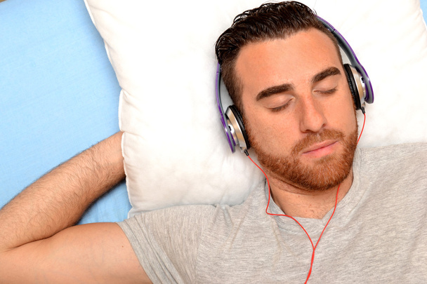 ember az ágyban fejhallgató - Fotó, kép