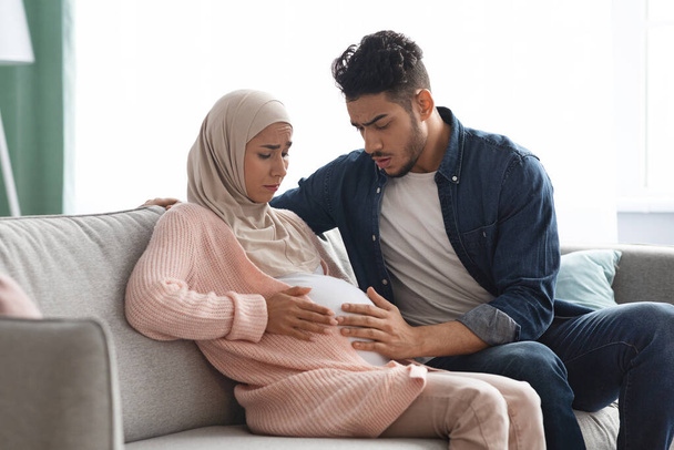 痛みを伴う赤ちゃんの動き。妊娠中のムスリム女性は自宅で腹部痛を患っています - 写真・画像