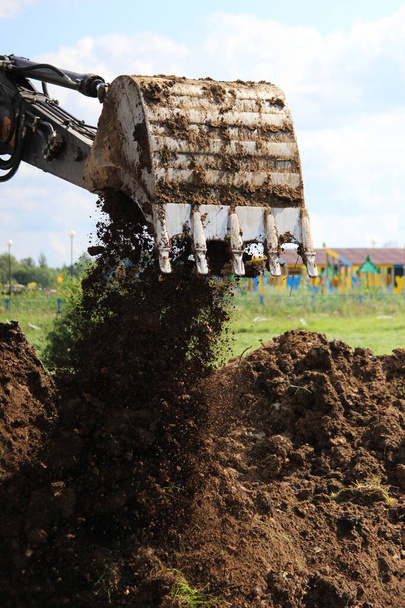 Ein Bagger gräbt auf einem freien Grundstück einen Graben aus. Verlegung der Pipeline zum neuen Haus. Dreharbeiten für Reportagen. - Foto, Bild
