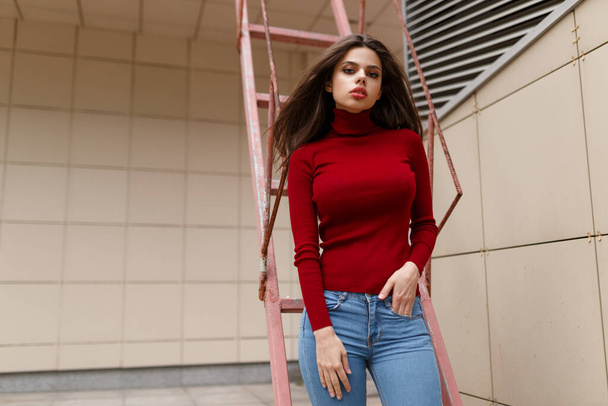 Gorgeous girl with big sexy lips, looking at camera, hair in wind in red sweater, over wall background. - 写真・画像