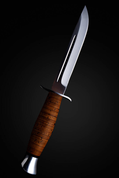 Koyu bir geçmişi olan tahta saplı bir av bıçağı. - Fotoğraf, Görsel