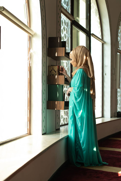 Young Traditional Muslim Woman Taking Quran in the Mosque - 写真・画像