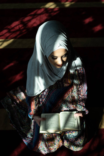 Muslim Woman Reading Koran or Quran Wearing Traditional Dress at the Mosque - Фото, зображення