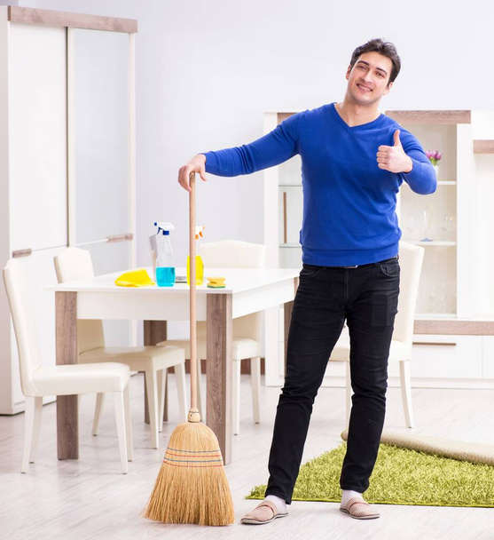 Młody człowiek sprzątanie podłogi miotłą - Zdjęcie, obraz