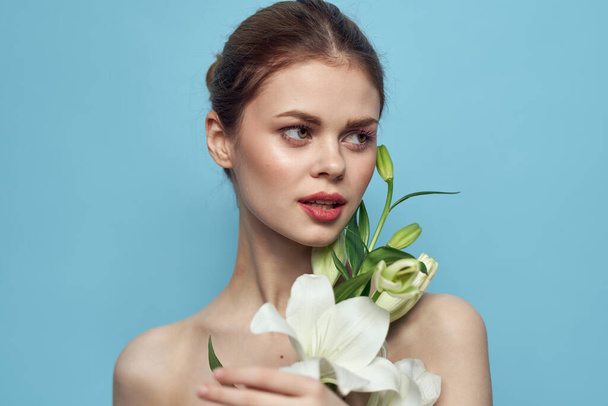 Woman with white flower on blue background cropped view of naked shoulders - Foto, imagen