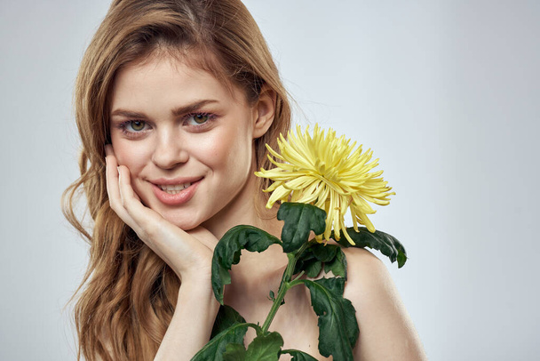Портрет красивої жінки з жовтою квіткою на світлому фоні чарівна модель посмішки червоне волосся
 - Фото, зображення