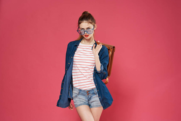 Красива жінка в окулярах модний одяг рюкзак рожевий фон моделі
 - Фото, зображення