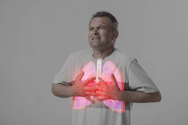 Άρρωστος ώριμος άντρας με πνευμονικά προβλήματα σε γκρι φόντο - Φωτογραφία, εικόνα