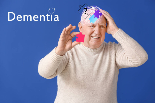 Homem idoso que sofre de deficiência mental com peças de quebra-cabeça em fundo de cor - Foto, Imagem