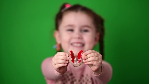 Das Kind untersucht und demonstriert eine Zahnplatte zur Straffung schiefer Zähne. - Filmmaterial, Video