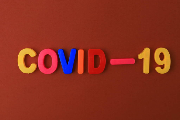 Slovo nebo text Covid-19 psaný v dětské abecedě s klasickými písmeny na magnetu. - Fotografie, Obrázek