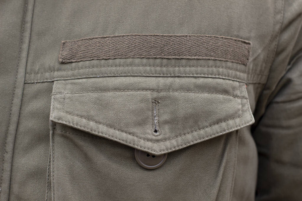 Chaqueta bolsillo primer plano costura botón verde, detalles de ropa caqui macro - Foto, imagen