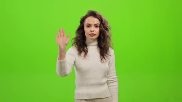 Η γυναίκα στέκεται και κοιτάζει την κάμερα. Σηκώνει το χέρι της και λέει σταμάτα. Στέκεται πάνω σε ένα πράσινο φόντο. Πράσινη οθόνη. 4K - Πλάνα, βίντεο