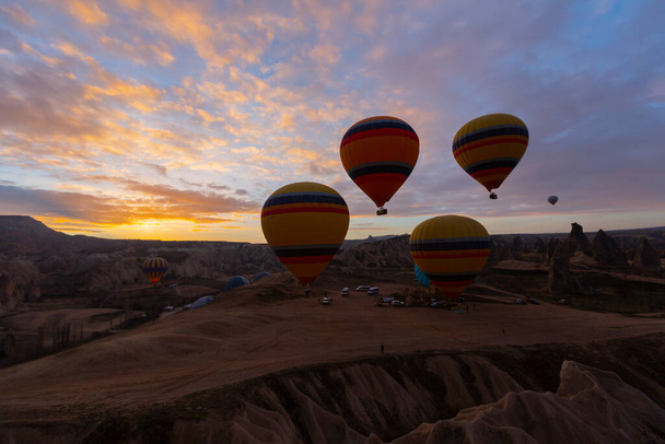 Widok panoramiczny niezwykłego skalistego krajobrazu w Kapadocji, Turcja. Kolorowe balony na gorące powietrze latają na niebieskim niebie nad niesamowitymi dolinami z bajkowymi kominami w Kapadocji. - Zdjęcie, obraz