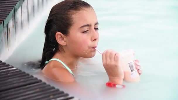 Chica joven relajante sorbiendo jugo de frutas en una piscina natural cámara lenta - Metraje, vídeo