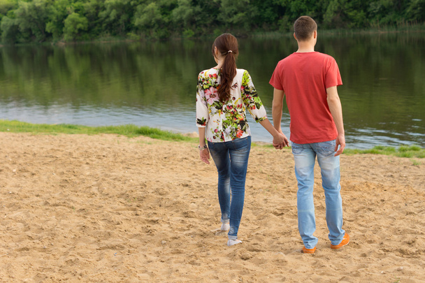Young couple walking towards the edge of the lake - Φωτογραφία, εικόνα
