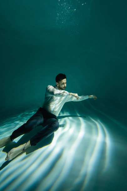 Muslimischer Geschäftsmann schwimmt mit Licht am Boden des Pools  - Foto, Bild