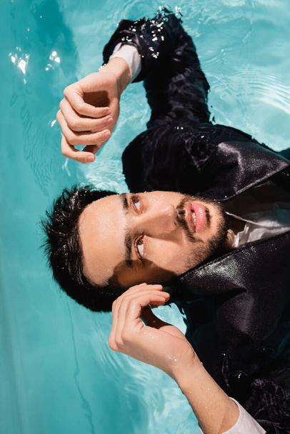 Arabian businessman in suit looking away in swimming pool  - Fotoğraf, Görsel