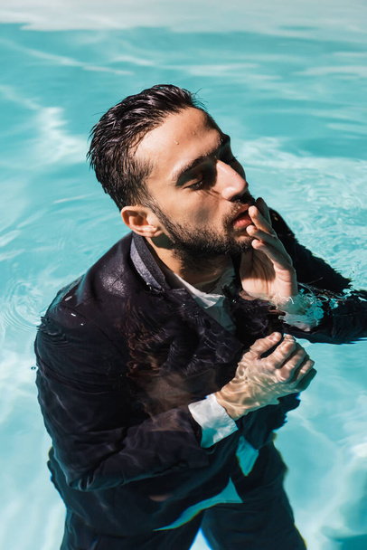 Muslim businessman touching lips in swimming pool  - Foto, imagen