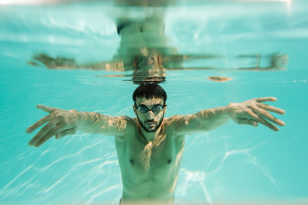 Arabian swimmer diving underwater with reflection  - Foto, Bild