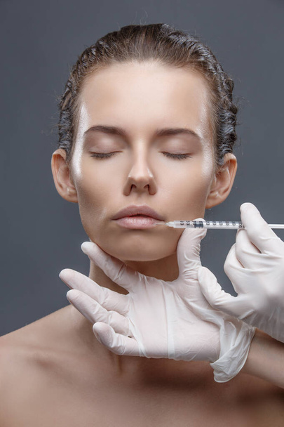 The doctor cosmetologist makes the Rejuvenating facial injections procedure for tightening and smoothing wrinkles on the face skin of a women in a beauty salon. Cosmetology skin care - Foto, imagen
