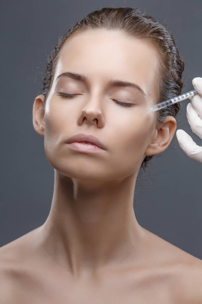 The doctor cosmetologist makes the Rejuvenating facial injections procedure for tightening and smoothing wrinkles on the face skin of a women in a beauty salon. Cosmetology skin care - Foto, afbeelding